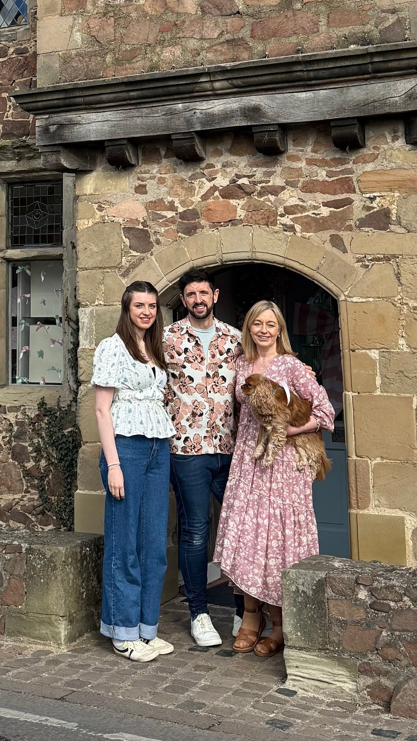Three people standing outside Narborough Hall on a clear day.