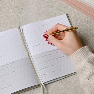 Hand writing in a notebook with a pen on a textured surface